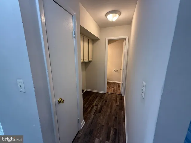 a view of a hallway with wooden floor and cabinets