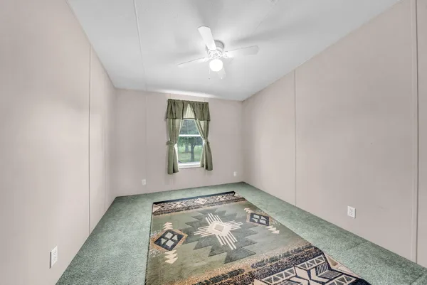 an empty room with a ceiling fan and window