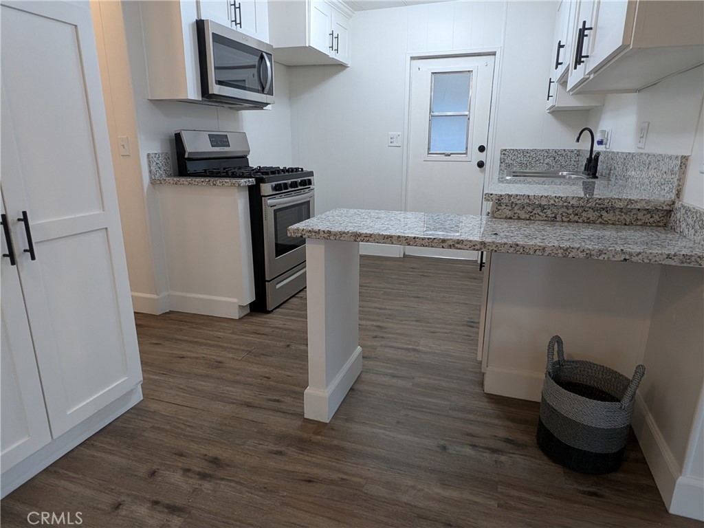 881 North Lake Street, Unit 357 Hemet, CA 92544 - Photo 9 of 29 a kitchen with kitchen island granite countertop wooden cabinets and a sink