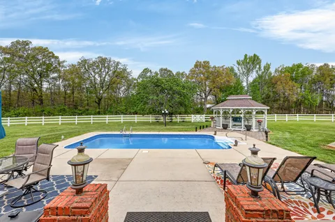 a view of a swimming pool with a bench and lawn chairs