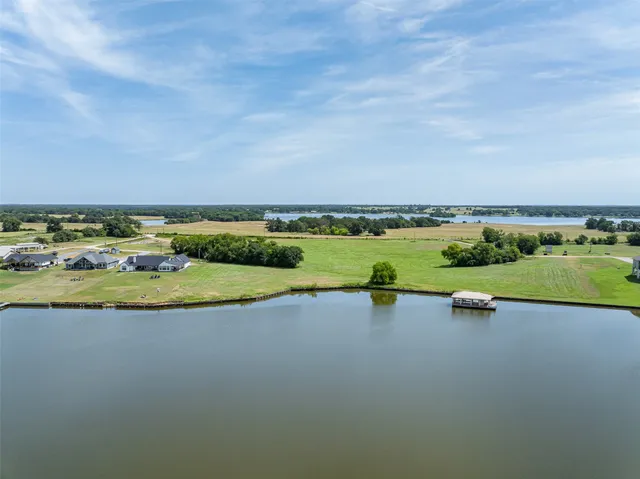 a view of a lake with lawn chairs and wooden fence