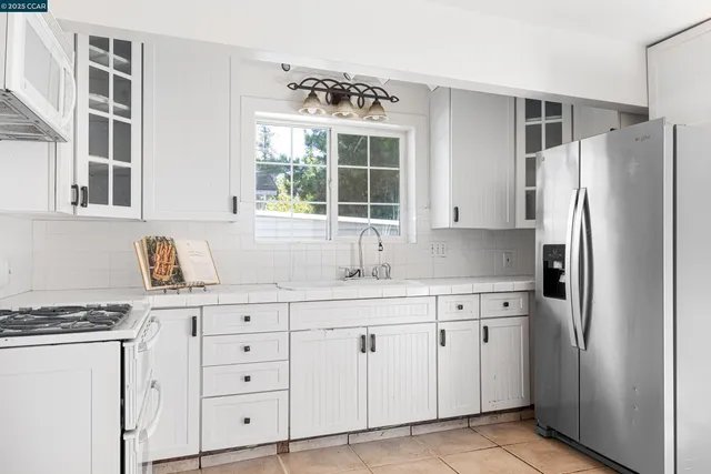 a kitchen with granite countertop white cabinets and refrigerator