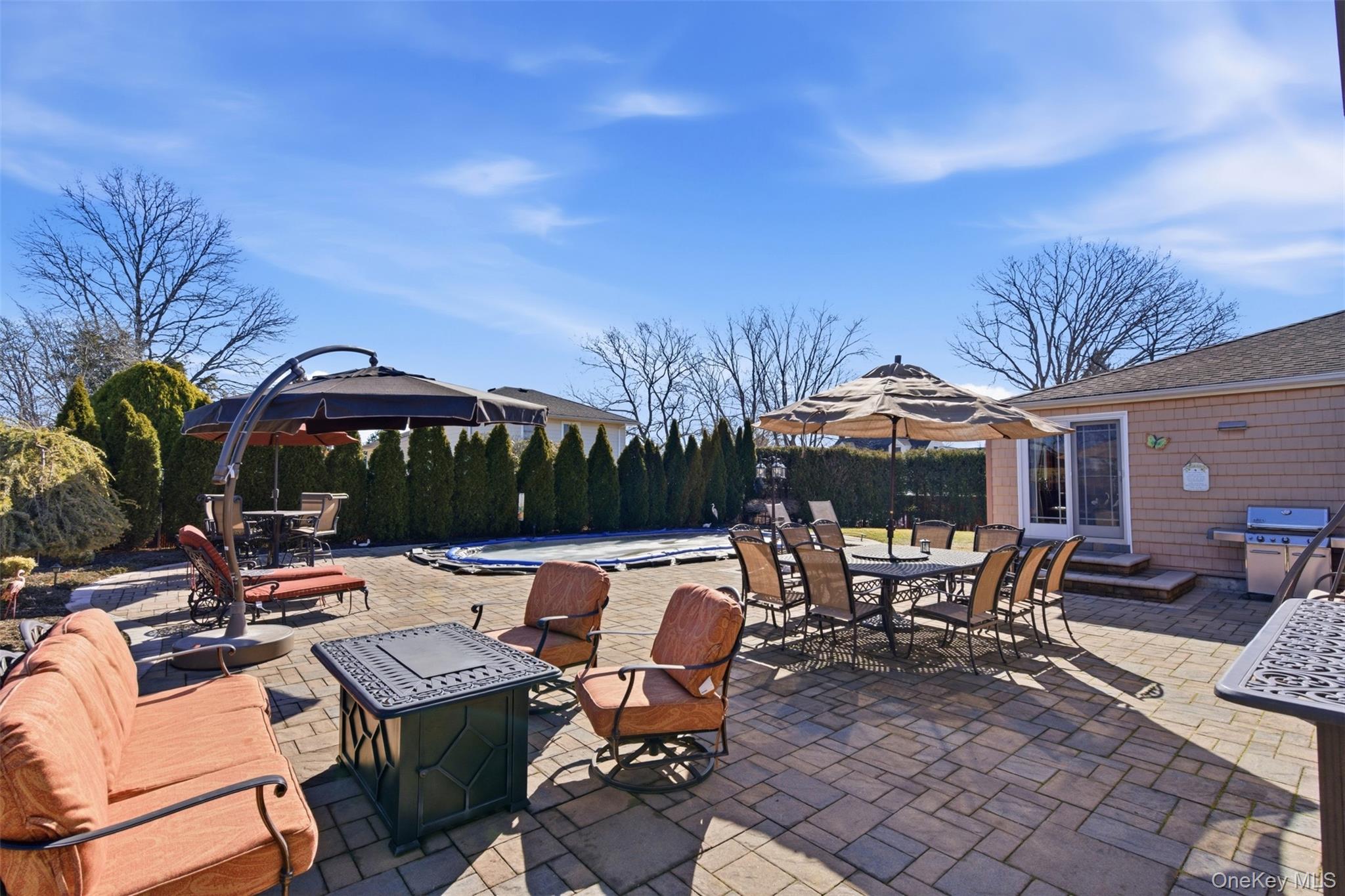 15 Leeward Lane Commack, NY 11725 - Photo 20 of 26 a view of a patio with table and chairs under an umbrella with barbeque grill and wooden fence