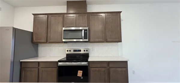 a kitchen with a sink a microwave a refrigerator and cabinets