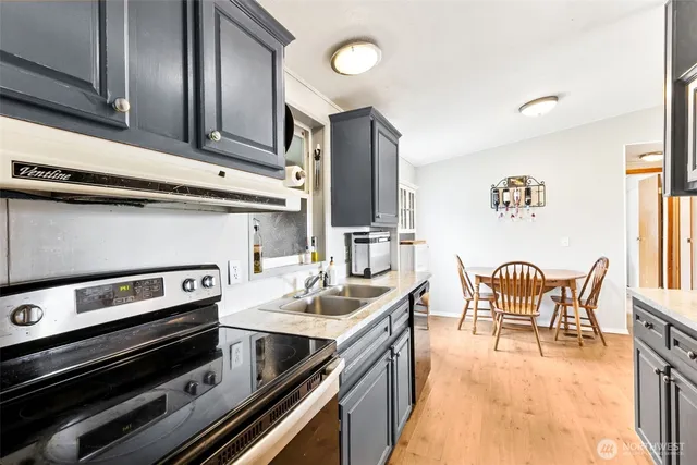 a kitchen with stainless steel appliances kitchen island granite countertop a refrigerator a stove top oven and couches next to a large window