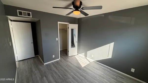 a view of empty room with wooden floor and ceiling fan