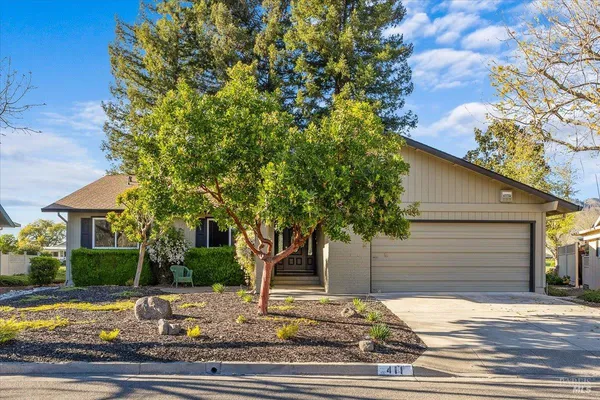 a view of a house with a tree tree and wooden fence
