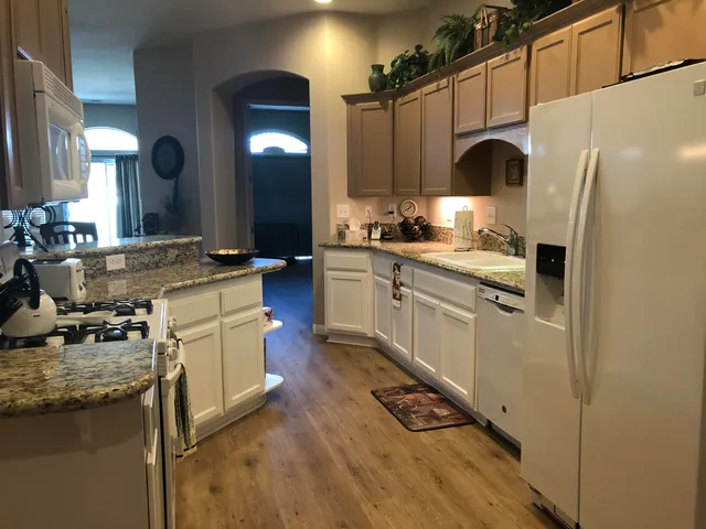 a kitchen with stainless steel appliances granite countertop a sink a stove and a refrigerator