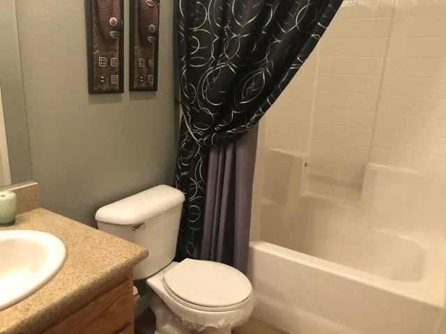 a white toilet sitting next to a bath tub and a shower