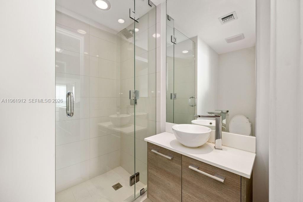 650 Northeast 32nd Street, Unit 2205 Miami, FL 33137 - Photo 16 of 56 a bathroom with a shower sink vanity mirror and toilet