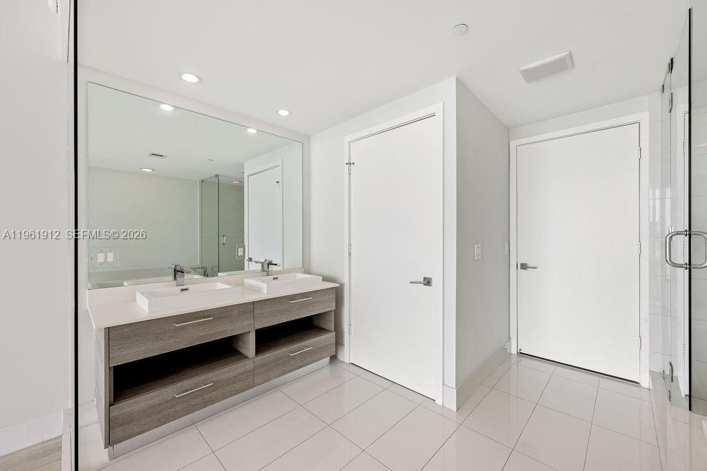 650 Northeast 32nd Street, Unit 2205 Miami, FL 33137 - Photo 10 of 56 a bathroom with a double vanity sink a mirror and a bathtub