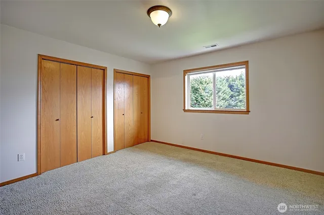 a view of an empty room with windows and closet