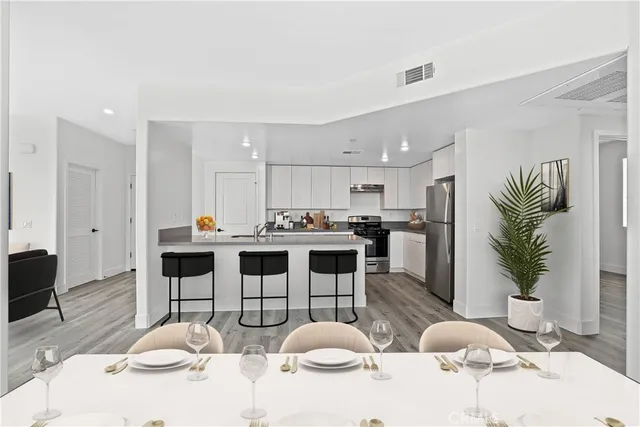 a kitchen with stainless steel appliances kitchen island granite countertop a refrigerator and a dining table