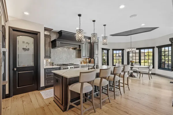 a kitchen with stainless steel appliances a dining table chairs and wooden floor