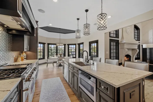 a large kitchen with stainless steel appliances granite countertop a stove a sink dishwasher a dining table and chairs with wooden floor