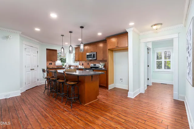 a kitchen with stainless steel appliances kitchen island granite countertop wooden floors and a view of living room