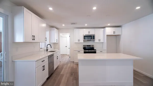 a kitchen with a sink a stove a refrigerator and white cabinets