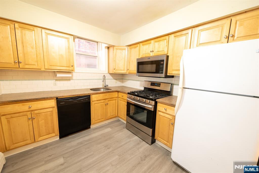 412 Walker Street, Unit 1 Fairview, NJ 07022 - Photo 2 of 10 a kitchen with stainless steel appliances granite countertop a stove a sink and a refrigerator