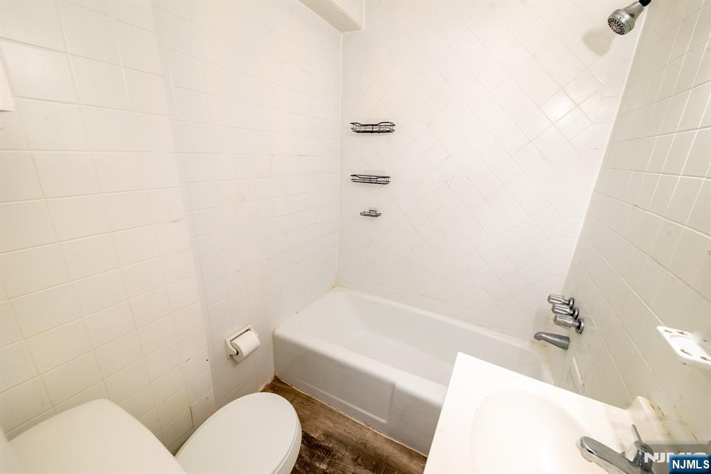 412 Walker Street, Unit 1 Fairview, NJ 07022 - Photo 4 of 10 a white toilet sitting next to a bath tub