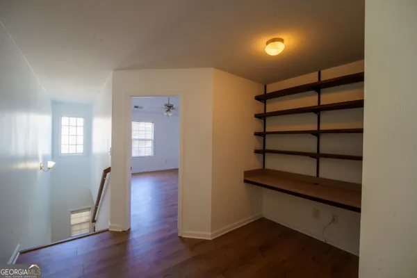 an empty room with wooden floor chandelier fan and windows