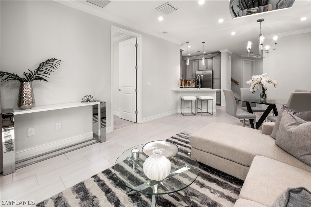 7587 Morgan Way Naples, FL 34119 - Photo 11 of 29 a living room with furniture and a dining table with kitchen view