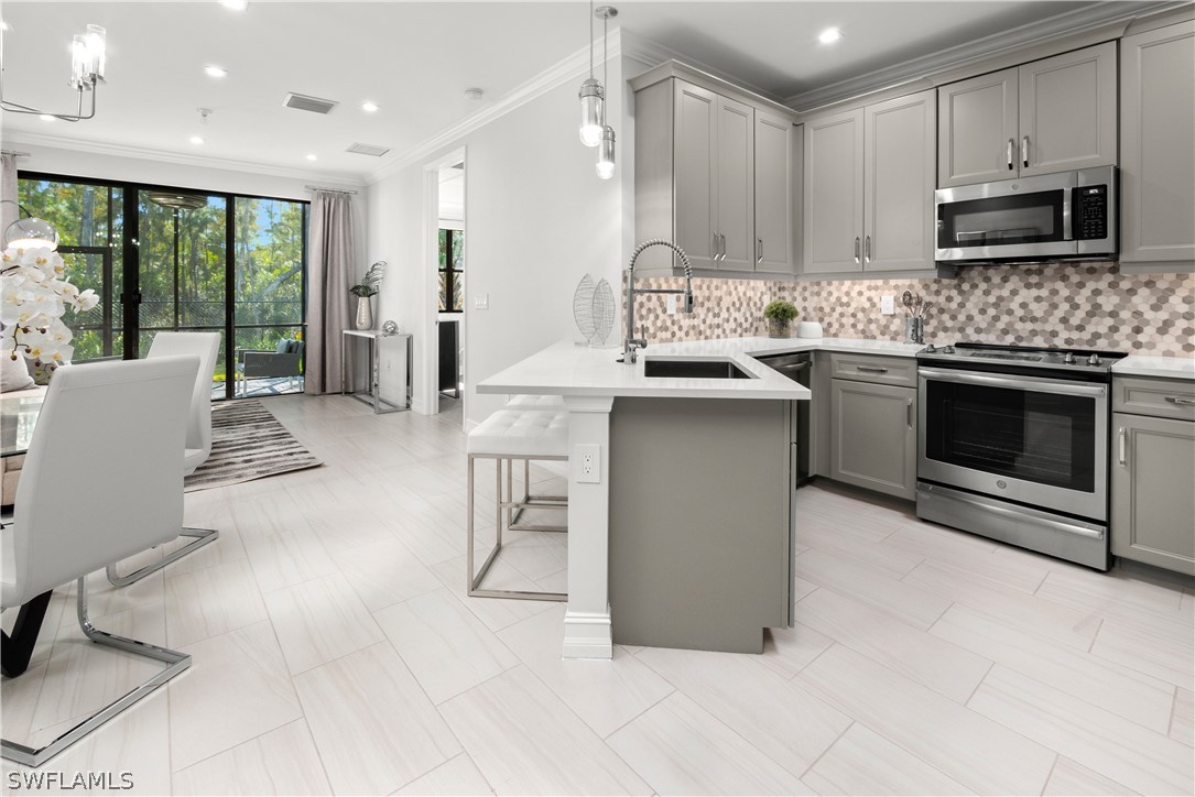 7587 Morgan Way Naples, FL 34119 - Photo 7 of 29 a kitchen with stainless steel appliances granite countertop a stove a sink and a microwave