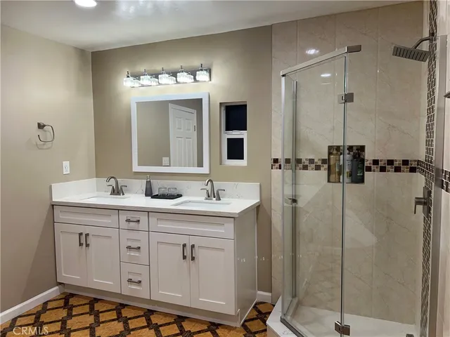 a bathroom with a double vanity sink mirror and shower