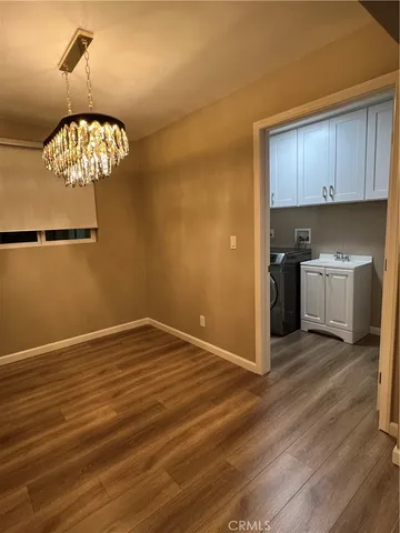 a view of kitchen and empty room with wooden floor