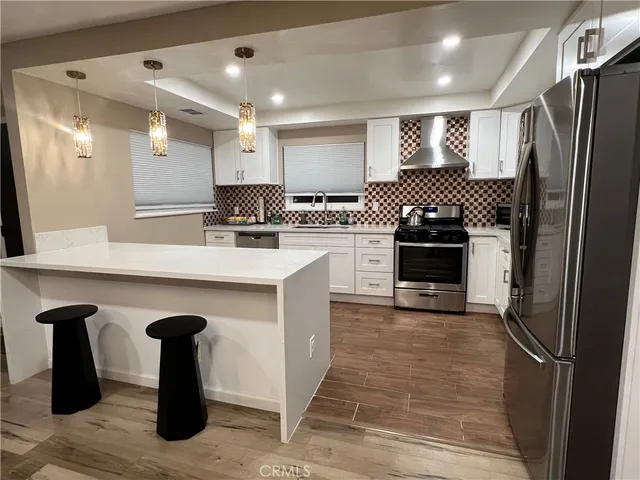 a kitchen with stainless steel appliances kitchen island granite countertop a refrigerator a sink and a stove