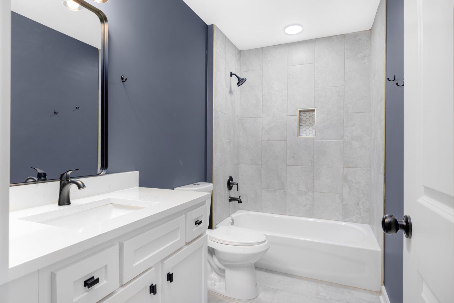 5702 Spring Lake Road Memphis, TN 38135 - Photo 32 of 40 Bathroom featuring a white vanity with integrated sink, dark hardware, and a framed mirror