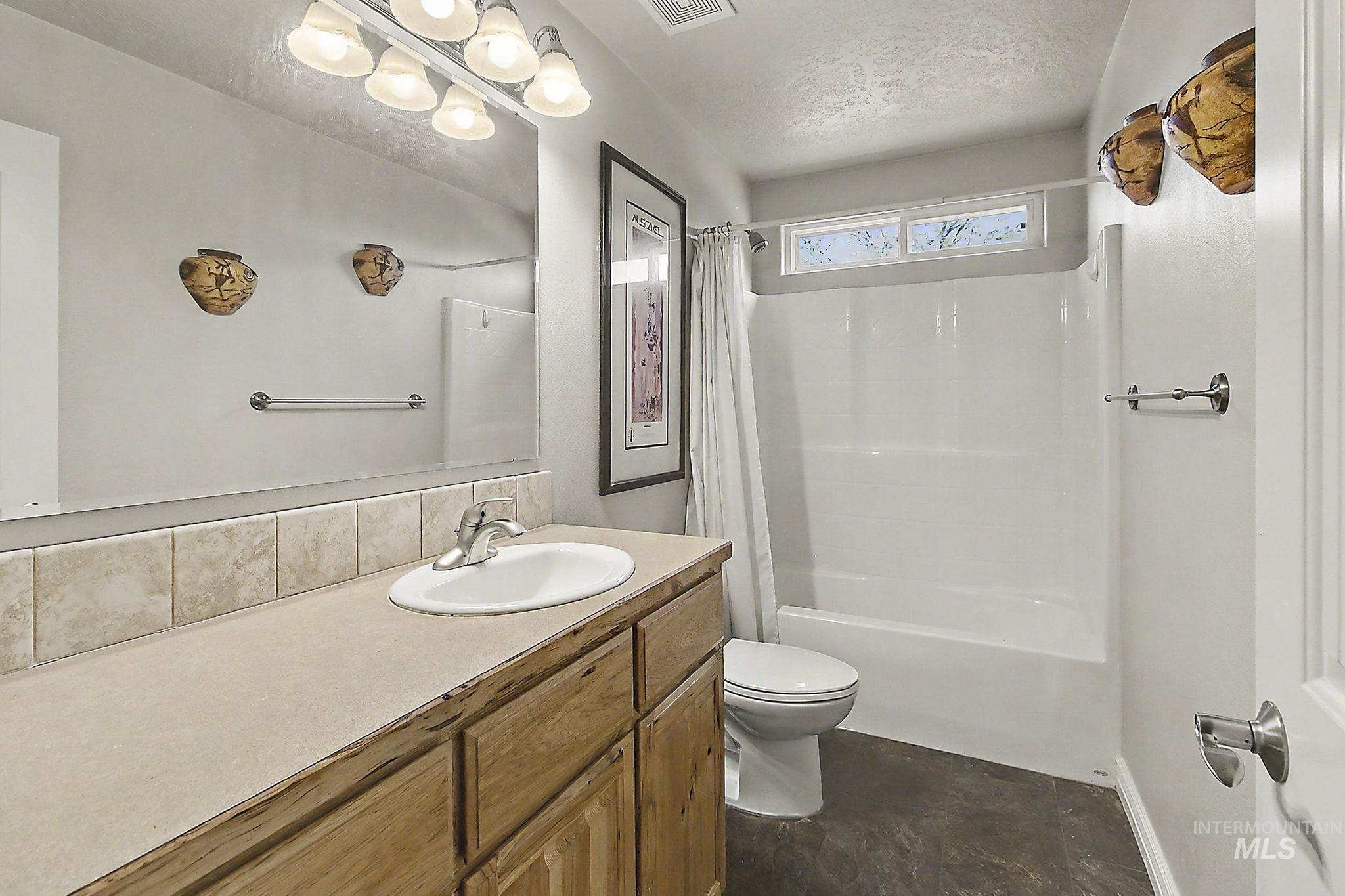 6900 West Charters Lane Melba, ID 83641 - Photo 25 of 49 Bathroom featuring a wood-finish vanity with an integrated sink, a large mirror, and a full bathtub with shower