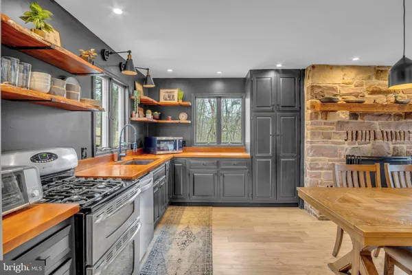 a open kitchen with stainless steel appliances granite countertop a stove refrigerator a dining table and chairs with wooden floor
