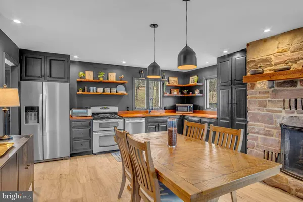 a kitchen with stainless steel appliances kitchen island granite countertop a table chairs and a refrigerator