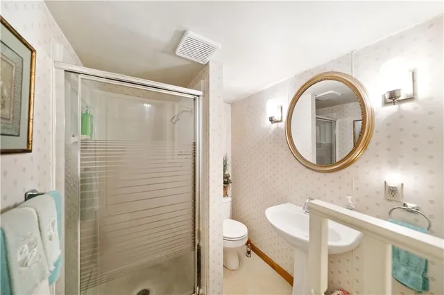 a bathroom with a toilet a sink a shower and a mirror