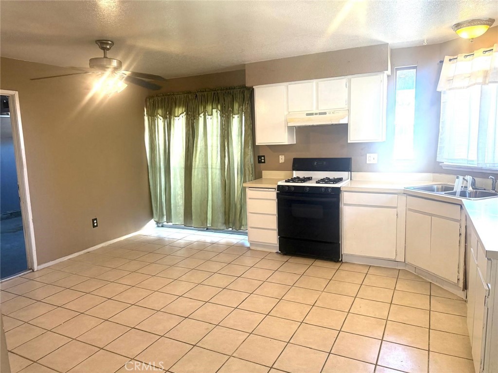 495 West 13th Street Perris, CA 92570 - Photo 14 of 32 a kitchen with a stove a sink and a refrigerator