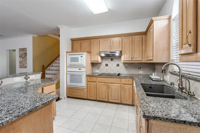 a kitchen with granite countertop a sink a stove and cabinets