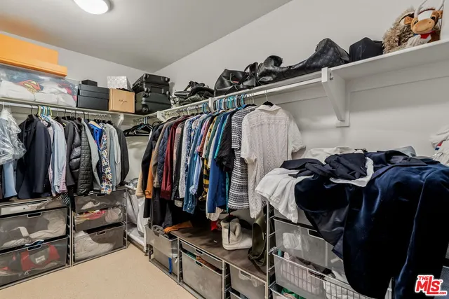 a view of walk in closet with clothes and shoes