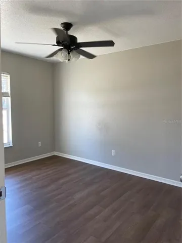 a view of a room with wooden floor a ceiling fan and window