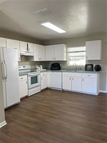 a kitchen with granite countertop a sink stove and refrigerator