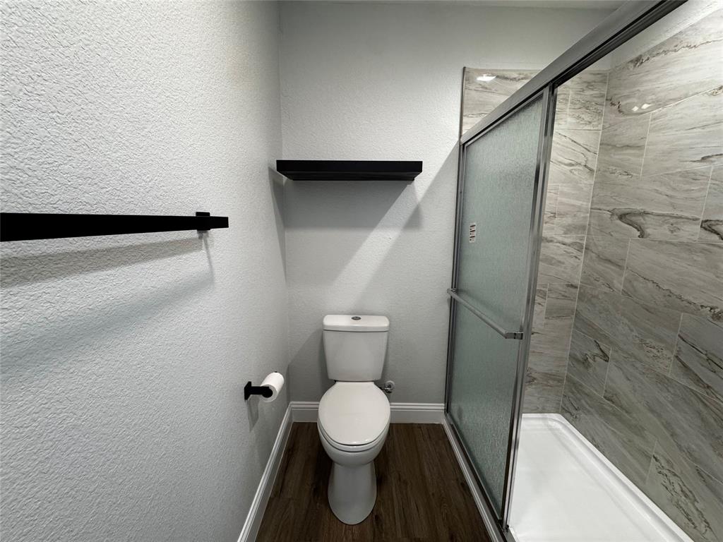 2909 Alexander Avenue Waco, TX 76708 - Photo 12 of 27 Full bathroom featuring a stall shower, a textured wall, and dark wood-type flooring