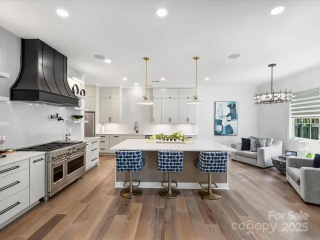 a large kitchen with stainless steel appliances granite countertop a stove a sink dishwasher a dining table and chairs with wooden floor