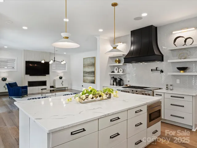 a kitchen with stainless steel appliances kitchen island granite countertop a sink a stove and a wooden floors