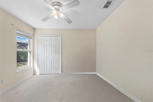 an empty room with windows and fan