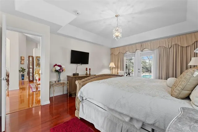 a spacious bedroom with a bed and a flat tv screen on dresser