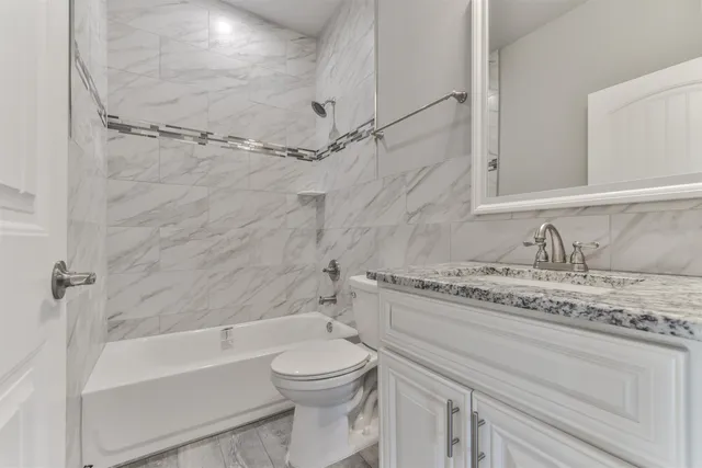 a large kitchen with stainless steel appliances granite countertop a stove a sink a refrigerator and white cabinets with wooden floor