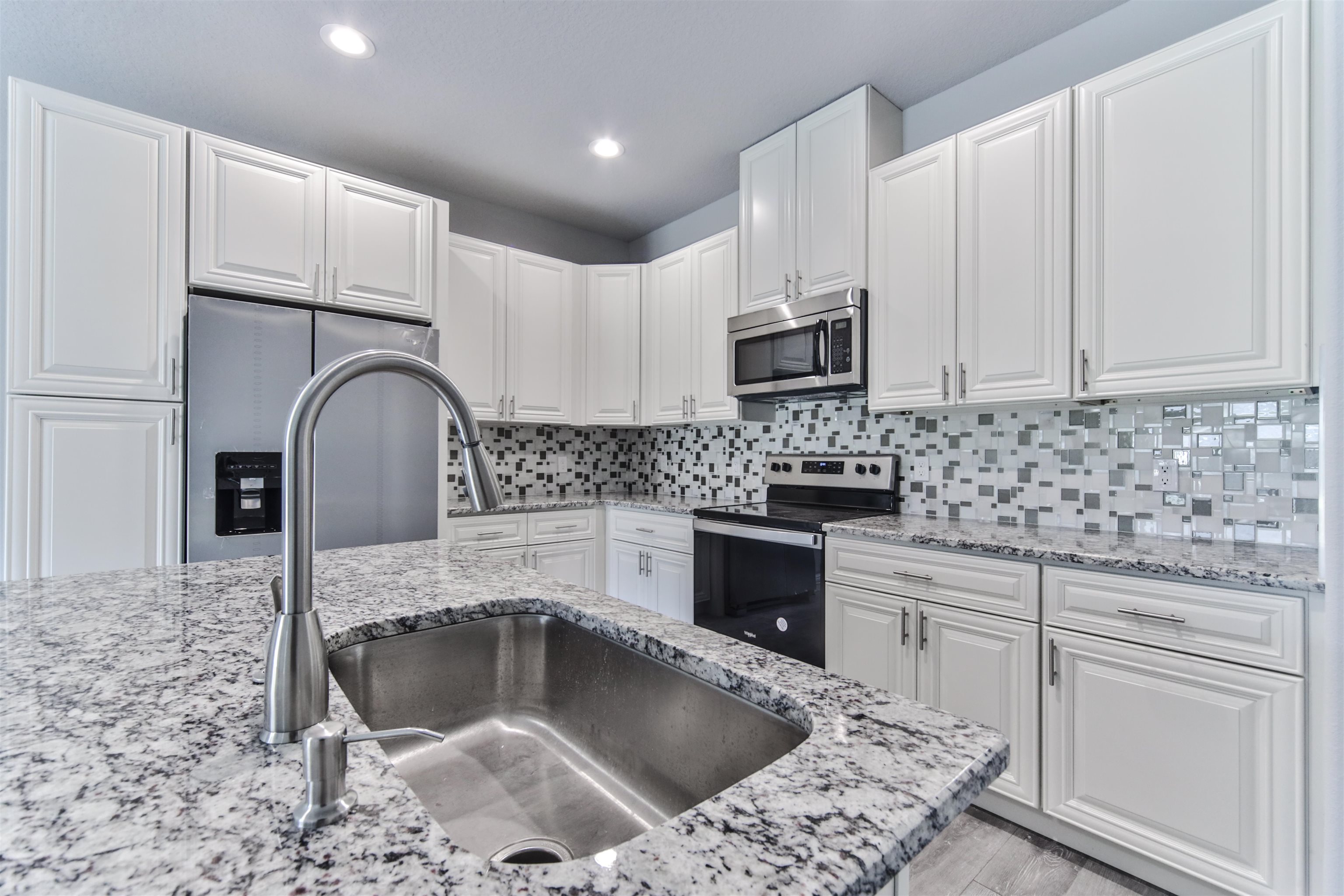 9 Seton Place Palm Coast, FL 32164 - Photo 16 of 37 a kitchen with granite countertop a sink a stove a microwave and cabinets