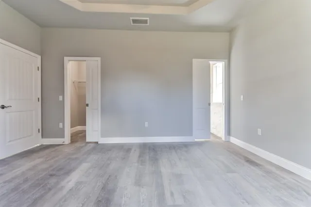 an empty room with wooden floor chandelier fan and windows