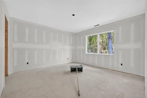 a view of an empty room with closet and a window