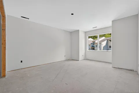 a view of empty room with window and painting on the wall