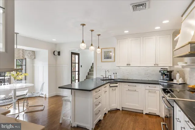 a kitchen with stainless steel appliances granite countertop a sink a microwave a dining table and chairs